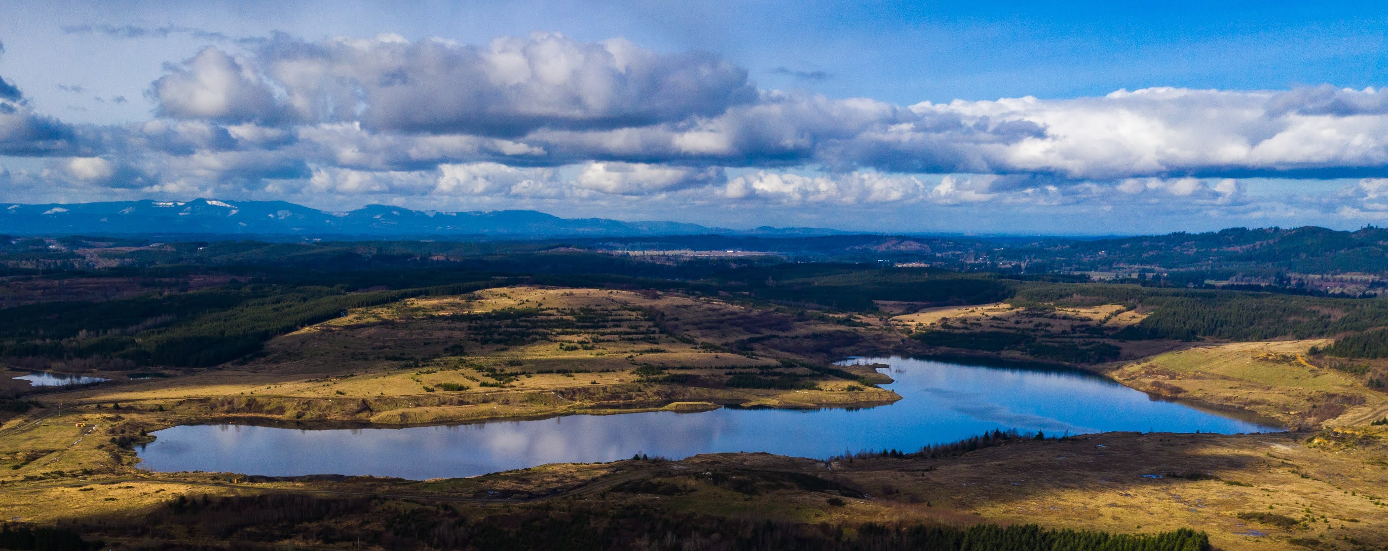 Lake Hanaford amongst rolling prairie with distant mountains in the background.